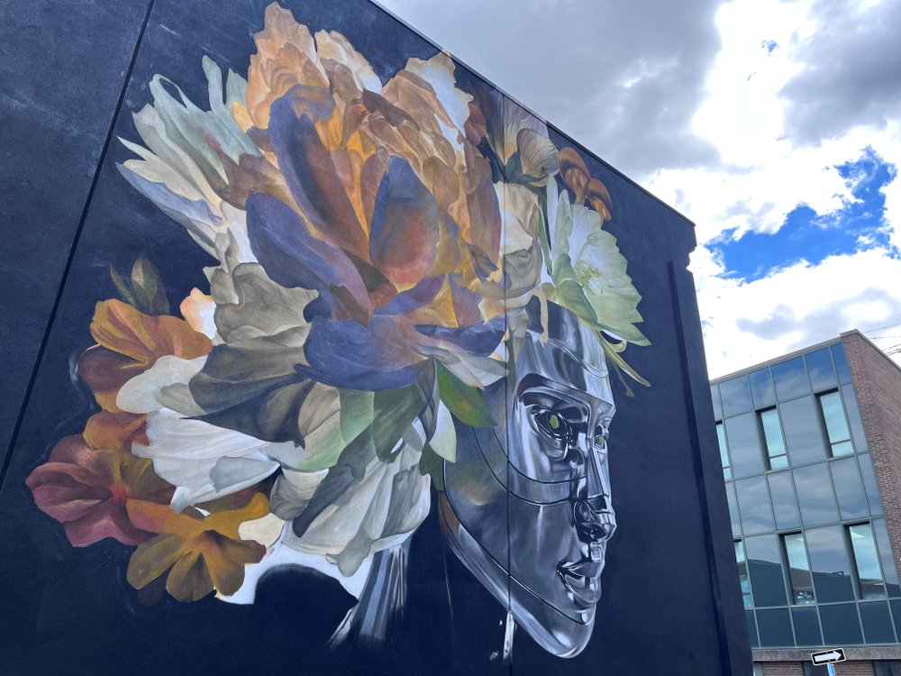Colourful mural with florals and robotic mask created by artist Bacon.