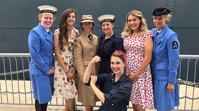 Women dressed in military and naval attire in front of HMCS Haida.