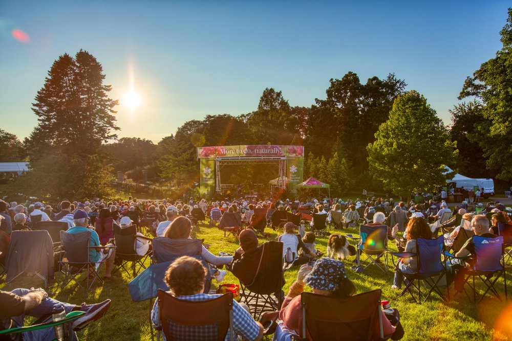 Crowd sitting on lawn in Royal Botanical Gardens before the start of a show.