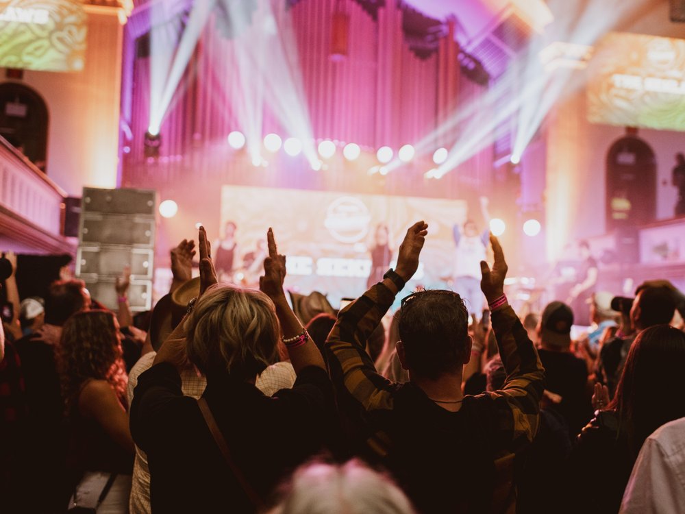 Audience member in front of the stage taking a picture of the artists performing at The Music Hall.