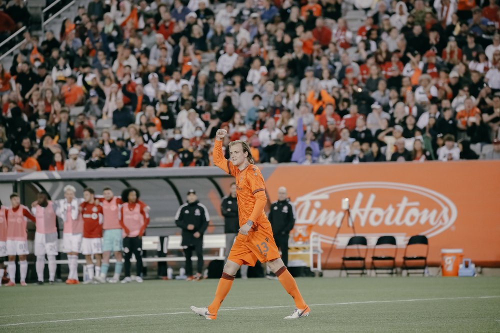 Forge FC player on field waving to fans.