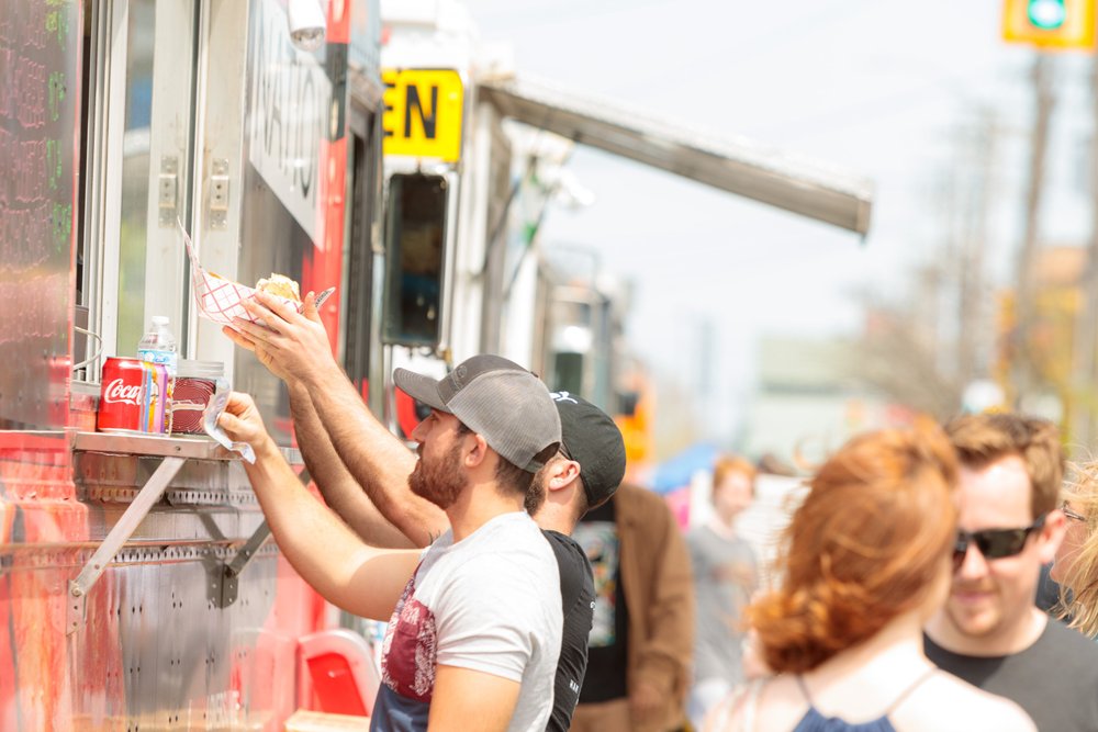 Young man reaching for order from food truck along Ottawa Street.