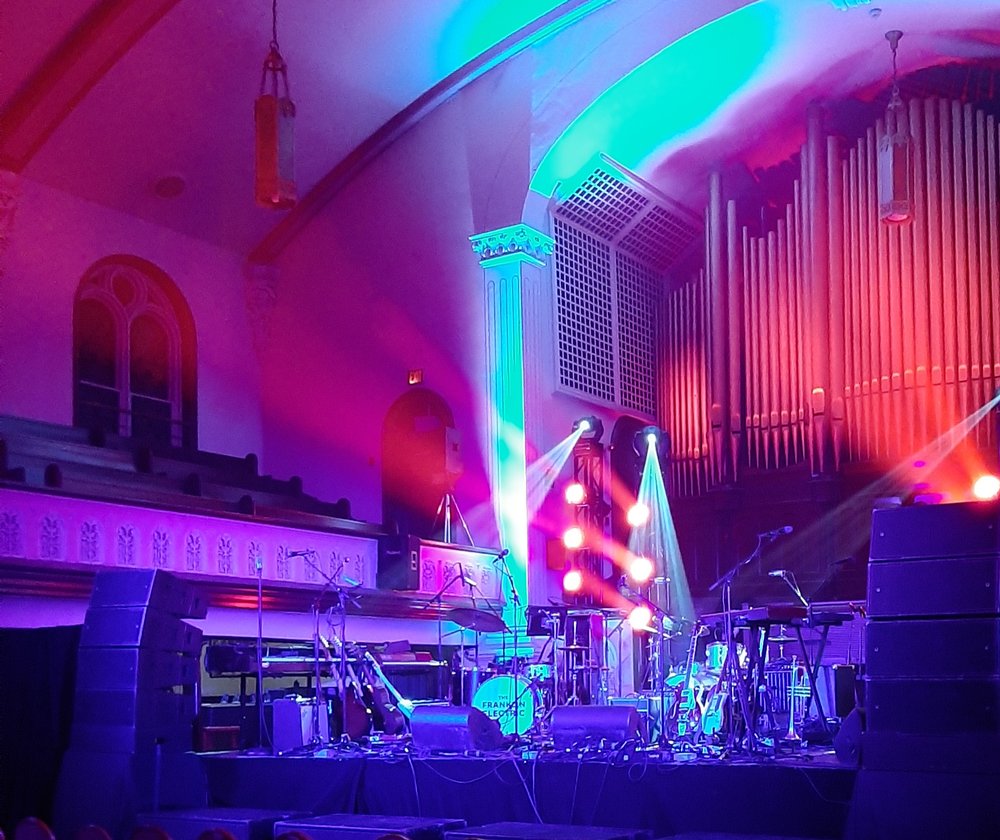 Concert stage lit up, filled with musical instruments.