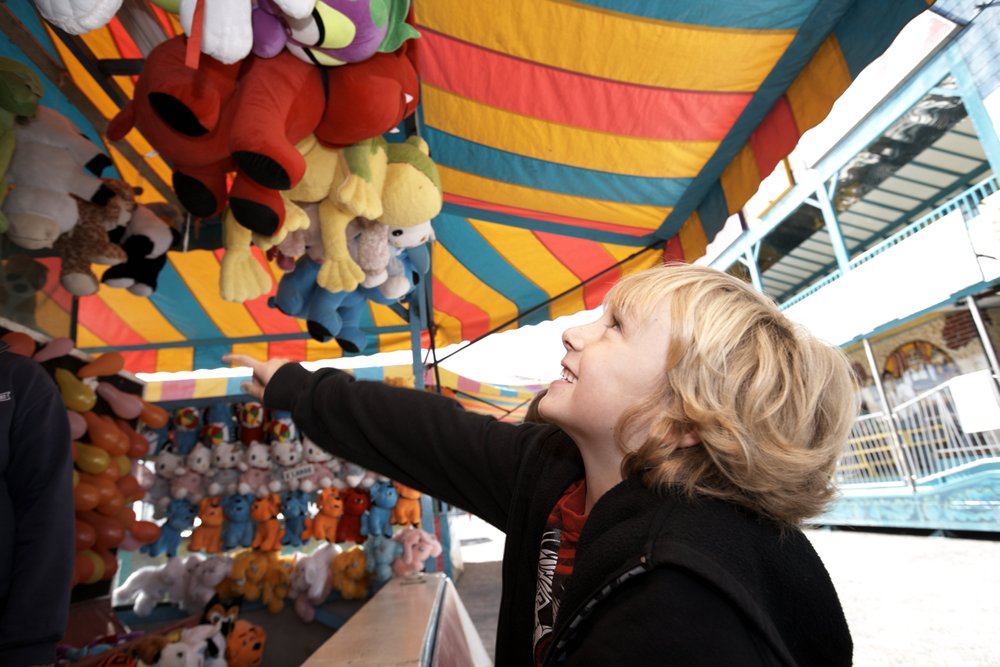 Young child reaching for a prize at a festival game.