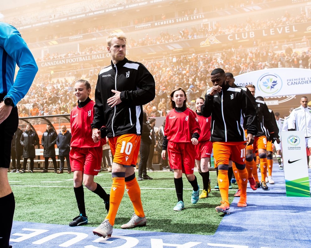 Forge FC players walking onto field before a match.