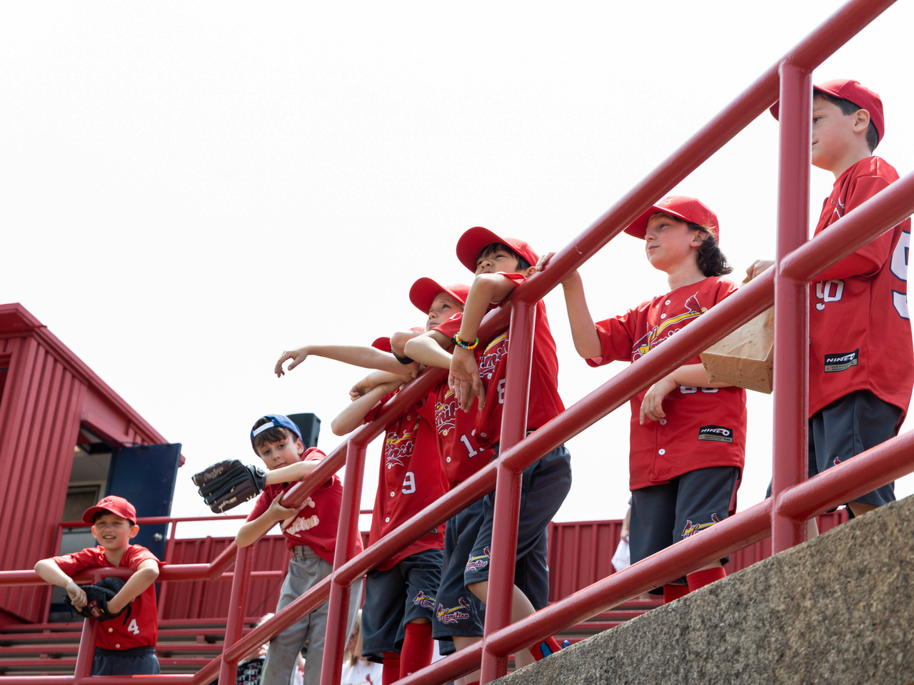 Group of kids lined up in the stands watching the game.