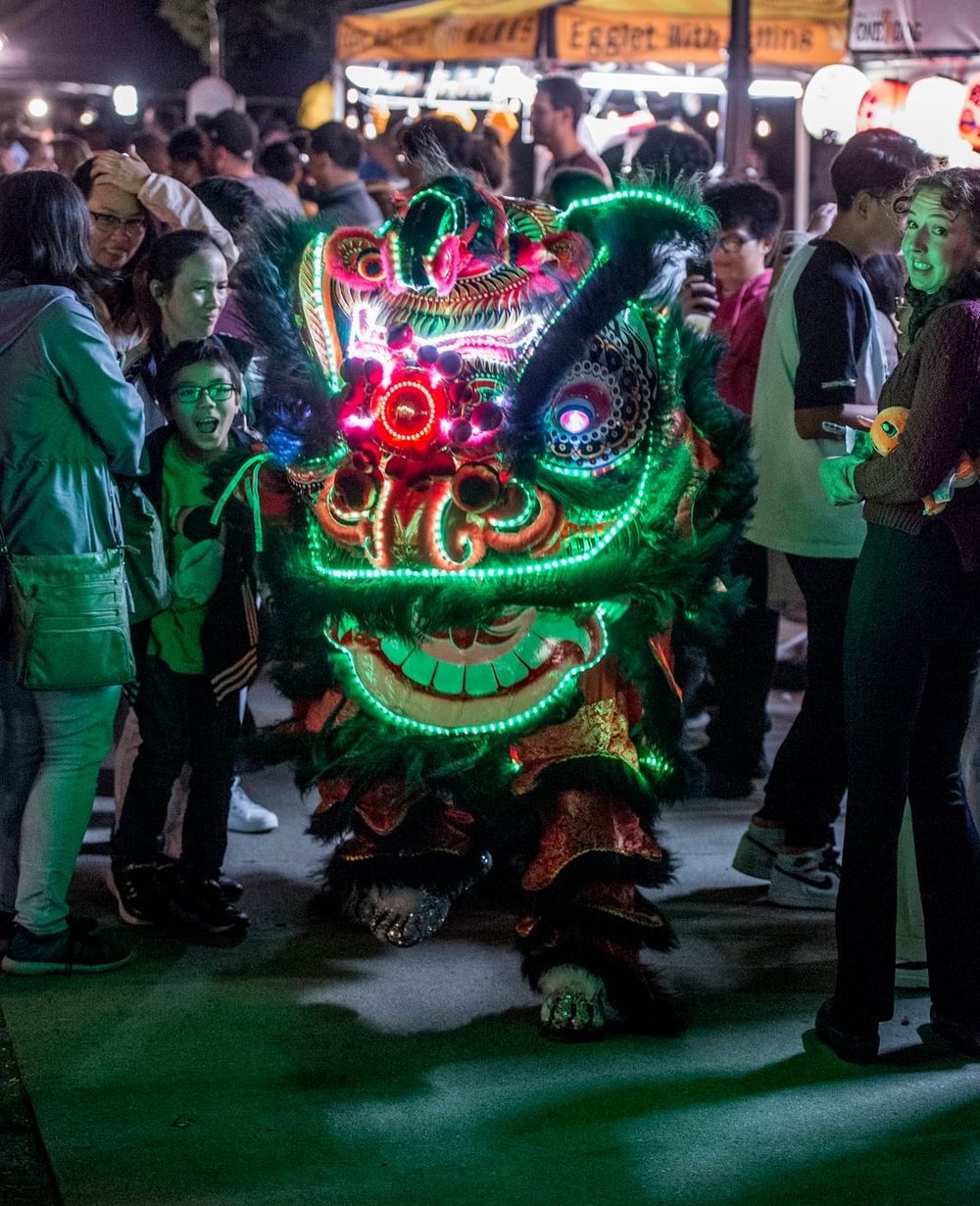 Dragon dancer making their way through the crowd in the evening at Lucky Lion Night Market.