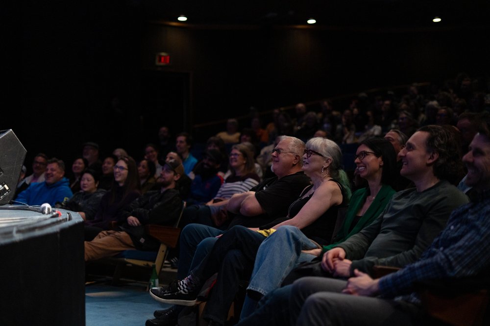 Audience sitting at a comedy show laughing and enoying the show.