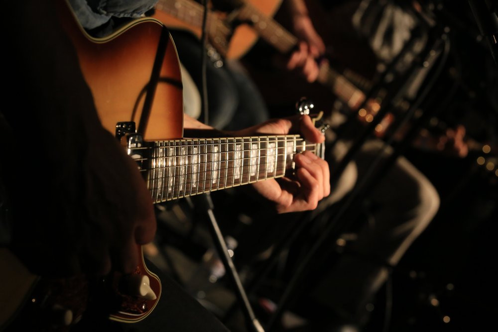 Close up shot of acoustic guitar being played on stage.