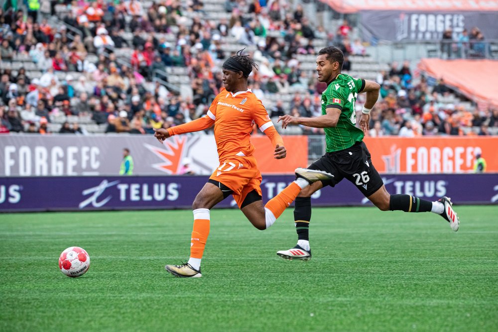 Forge FC player on field kicking the ball mid-play.