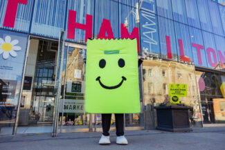 Mascot posing in front of the Hamilton Farmers Market.