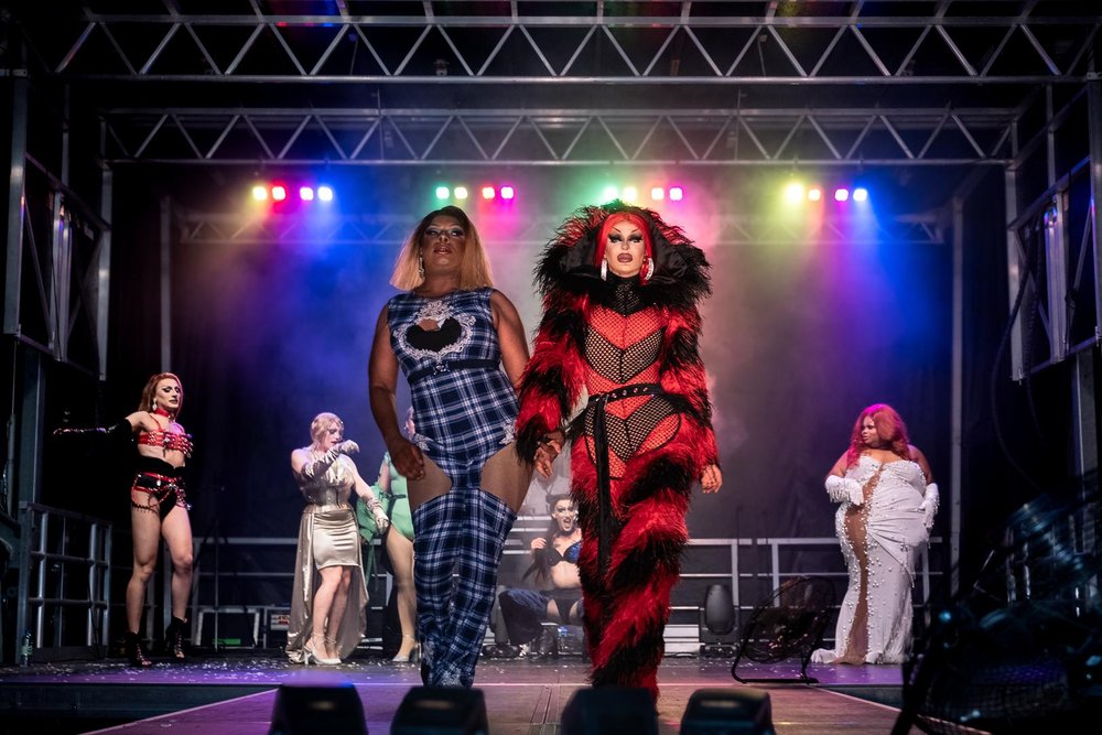 Drag performers in colourful costumes walking on stage at Pride at the Pier.
