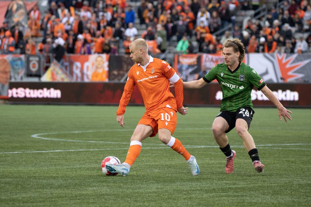 Forge FC player kicking a ball on field.