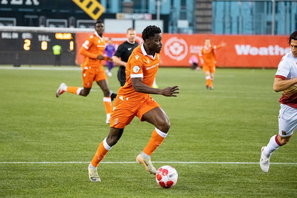 Forge FC player kicking a ball in play on the field