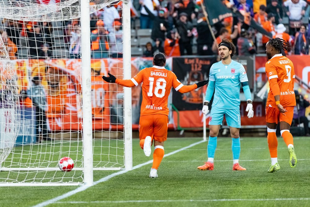 Forge FC players by net on field mid-play.
