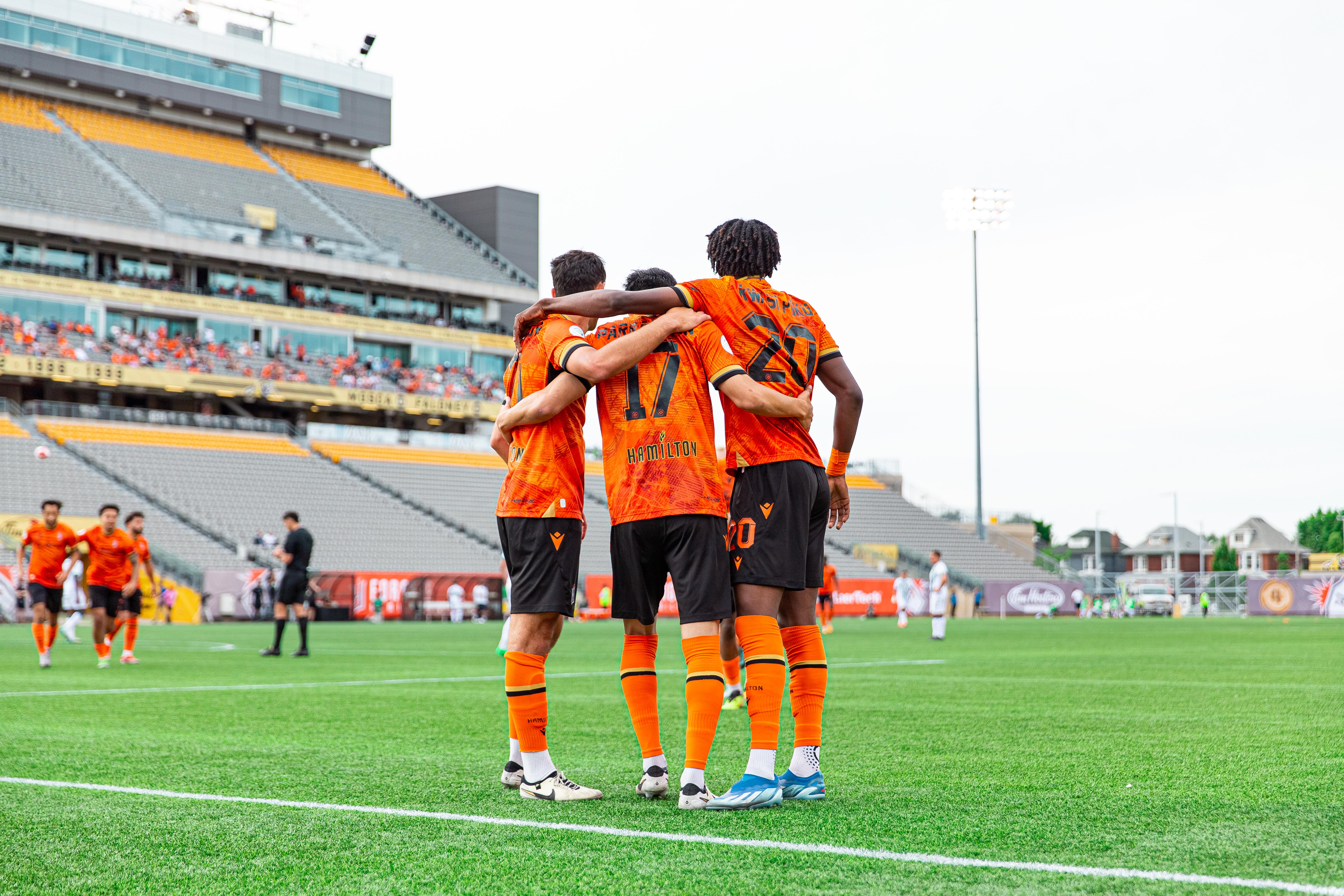 Forge FC Players huddled on field.