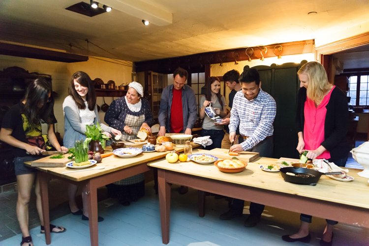 People gathered around a table in the Dundurn Castle preparing food.