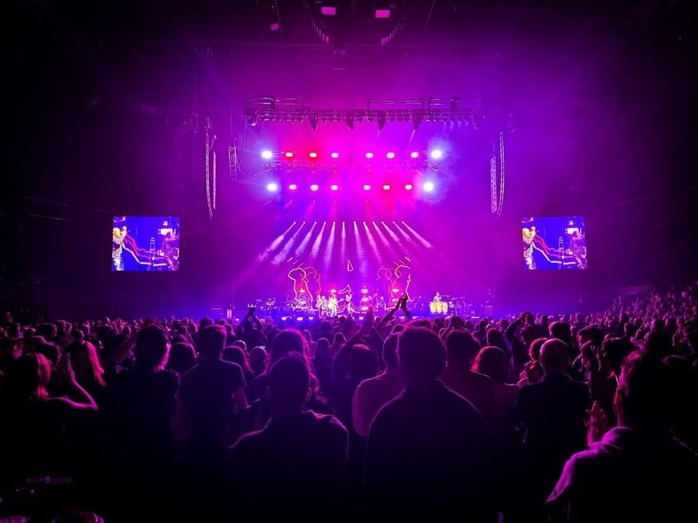 Full crowd on the floor during concert at TD Coliseum with full lights on stage and band playing.