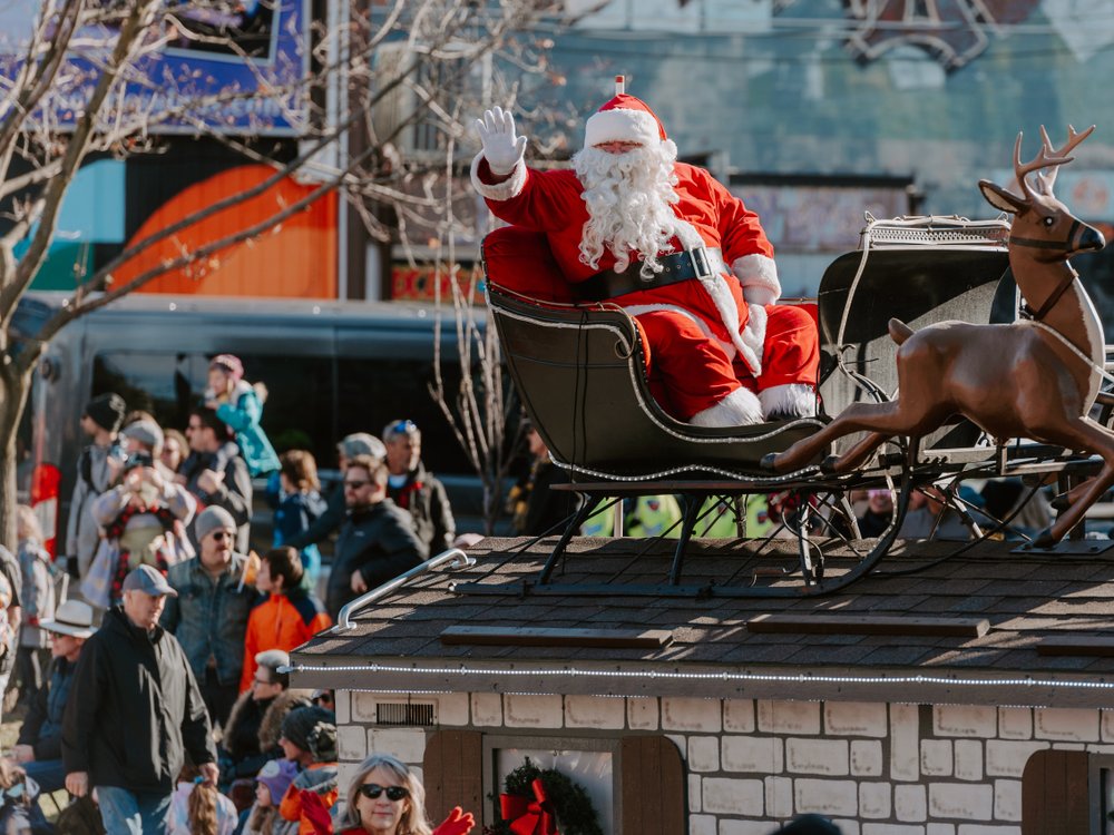 Santa Clause on sleigh waving to crowd at the parade.