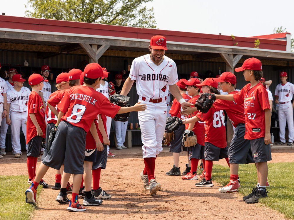 Hamilton Cardinals player coming onto field between two rows of kids giving them high fives.
