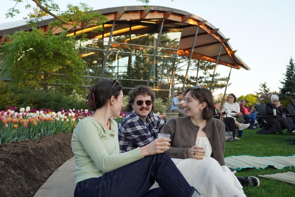 Friends sitting on the grass at RBG After Dark in the Rock Garden.