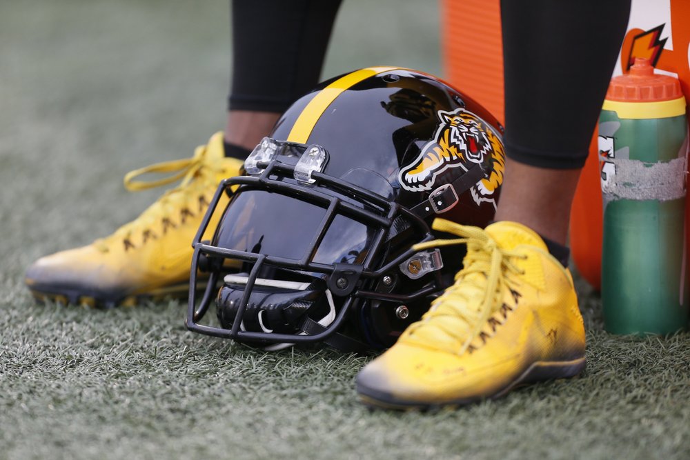 Black and gold Ti-Cats helmet and shoes on field.