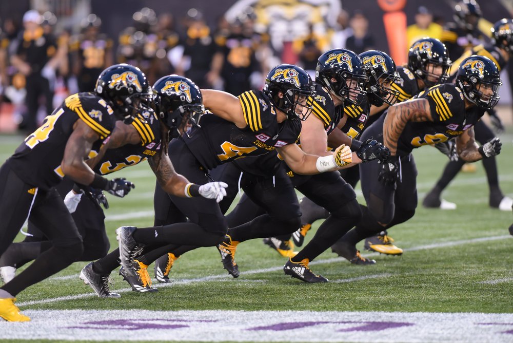 Tiger-Cats at the line of scrimmage on field.