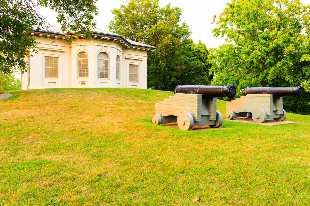 Tow black cannons sitting on the green lawn in front of the Hamilton Military Museum