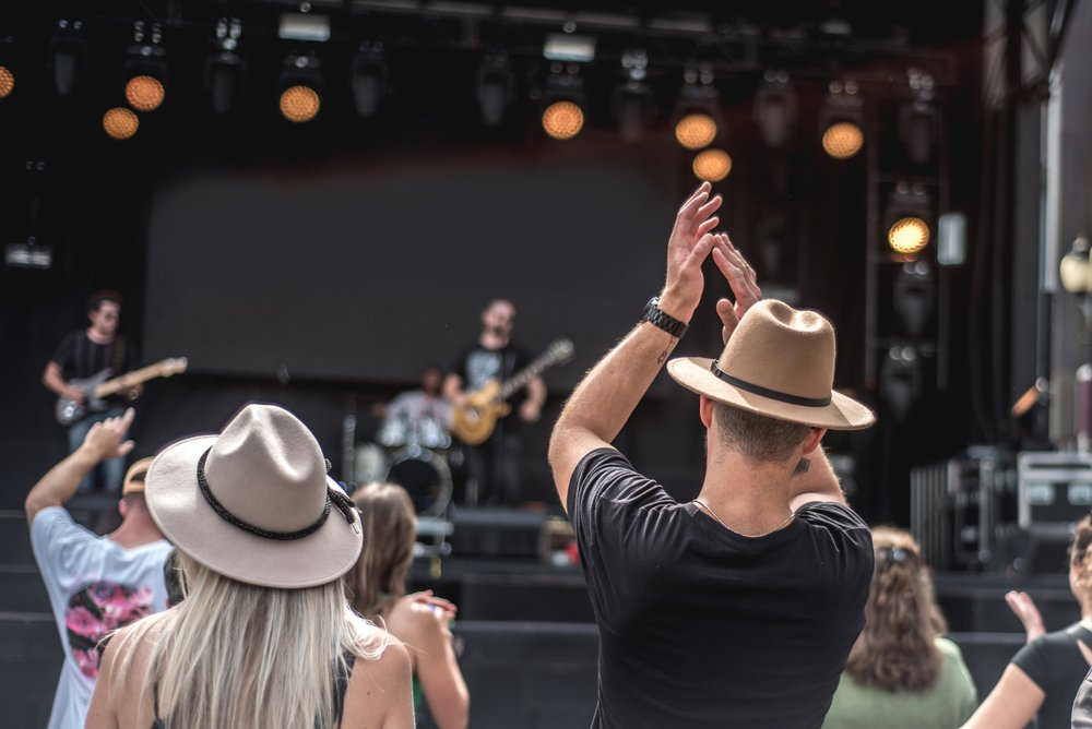 People clapping at musician on stage at outdoor festival.