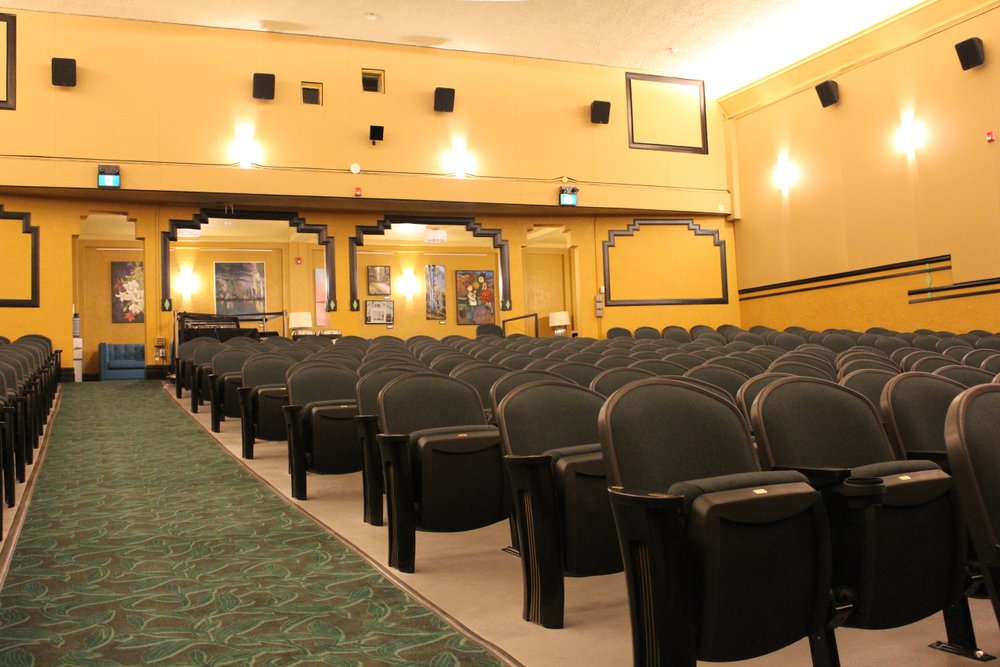 Green theatre chairs surrounded by yellow walls inside of Westdale Theatre.