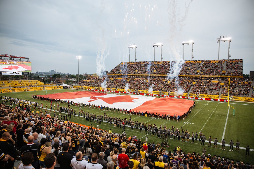 Canadian flag on the field with fireworks at the start of the game.